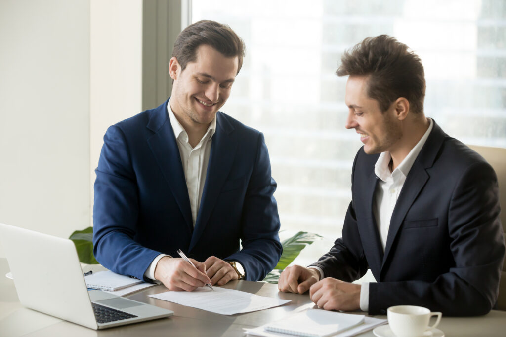 Professionals reviewing and signing documents for ISO 27001 certification compliance