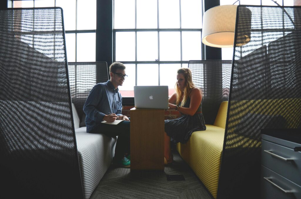 Two professionals collaborating on a laptop in a modern office, discussing ISO 14001 environmental management certification.