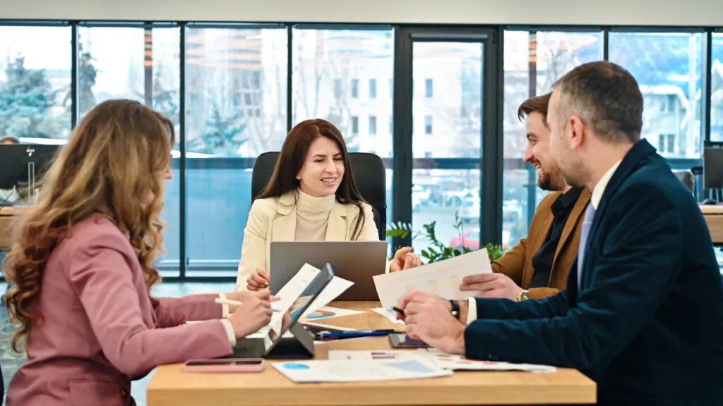 A HACCP team meets in a bright, modern office to review documents and collaboratively discuss the development and implementation of their food safety plan