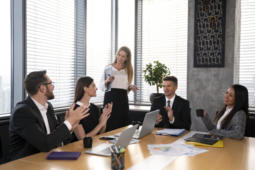 A team of business professionals in a boardroom clapping and smiling, celebrating the successful achievement of their HACCP certification