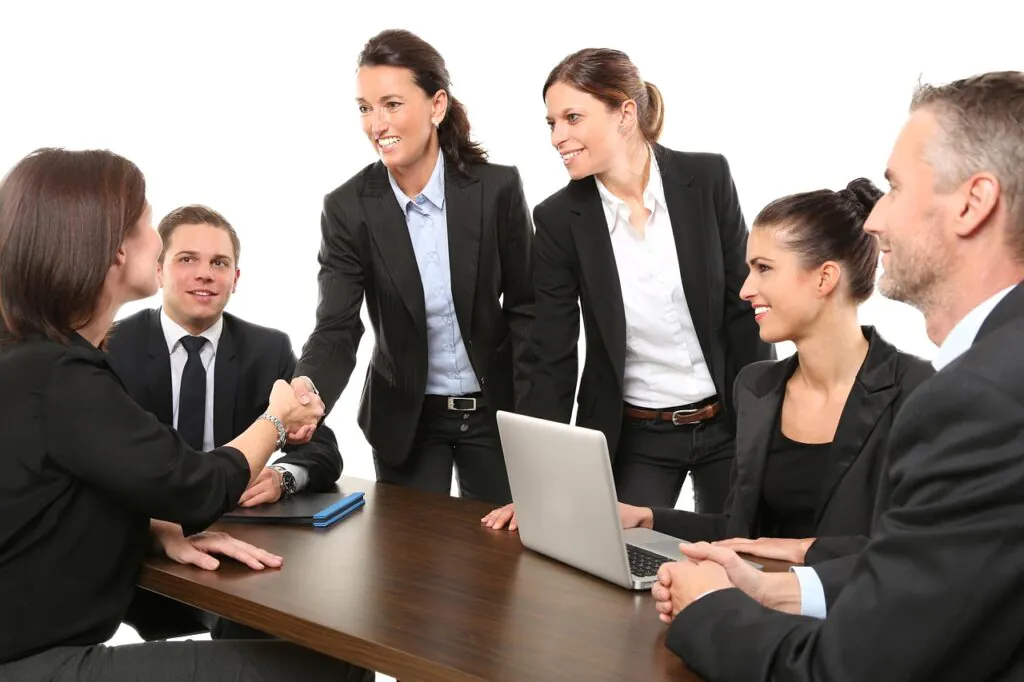 Business professionals shaking hands across a conference table, symbolizing the trust and partnership established during a successful SOC 1 audit engagement.
