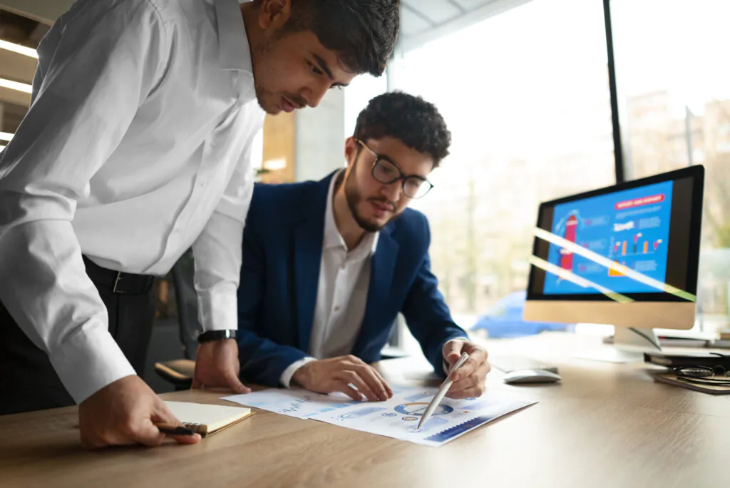Two colleagues collaborating and reviewing data charts on a desk