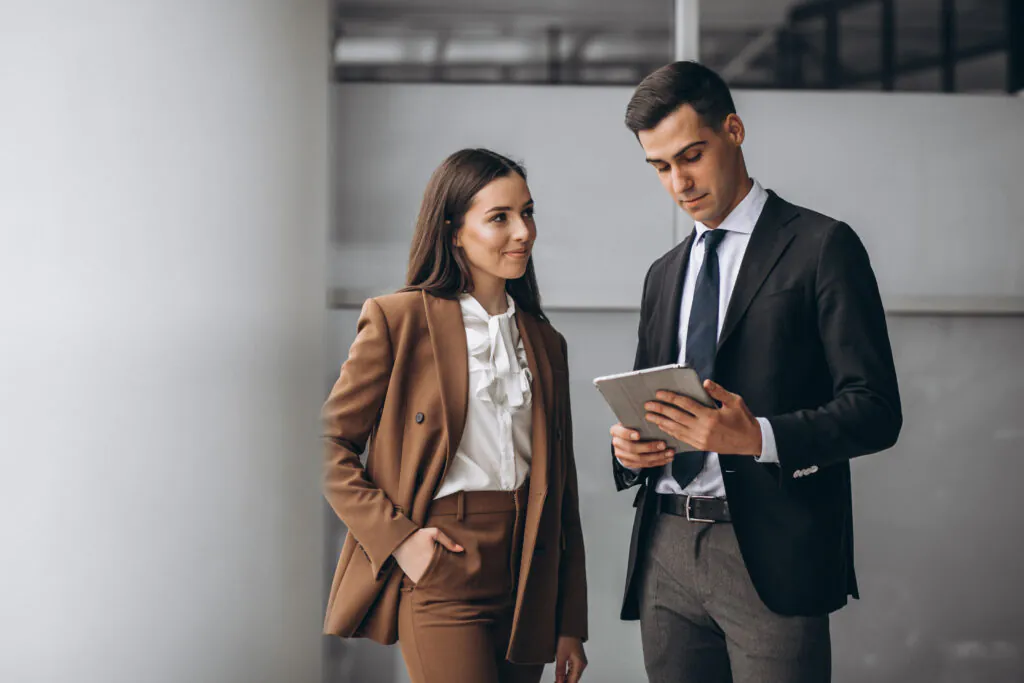 Two colleagues stand and review a tablet, possibly looking at their organization's newly published SOC 3 report or trust seal